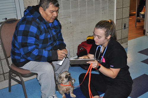 A pet owner and his dog visit with a U of M veterinary student.