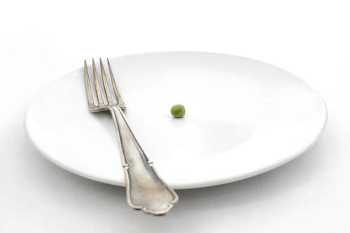 A single pea on a white plate with a fork on it.