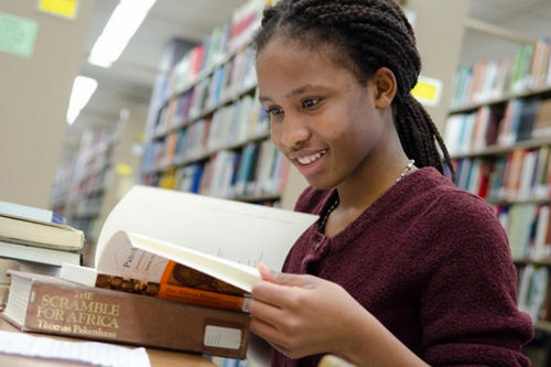 A young female student looks at a book in Wilson Library.