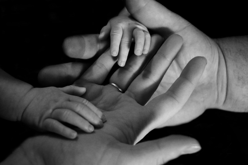 Adults hands holding a small child's hands.
