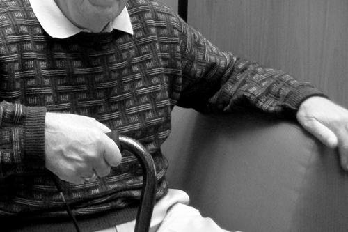An elderly male patient with Parkinson’s disease grasps a walker.