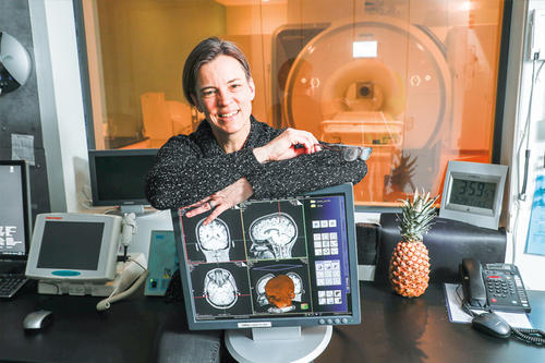 Cheryl Olman poses with brain diagrams and a pineapple.