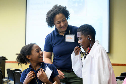 Dr. Renée Crichlow stands with two students, one wearing a stethoscope.