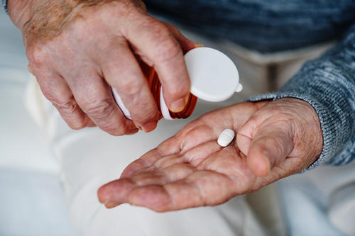 Elderly hands with prescription pill bottle. 