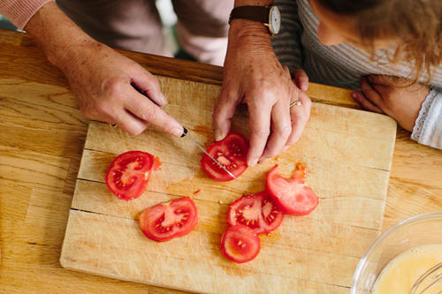Family members slice tomatoes on a cutting board.