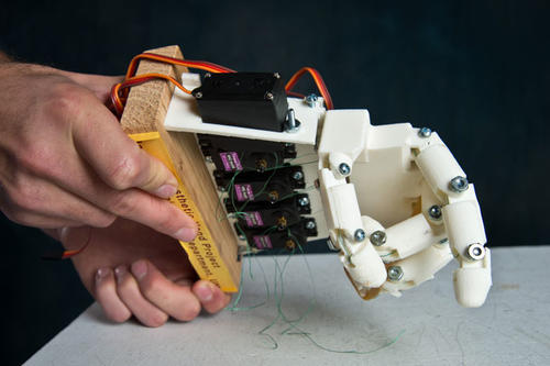 Human hand holding a robotic hand. 
