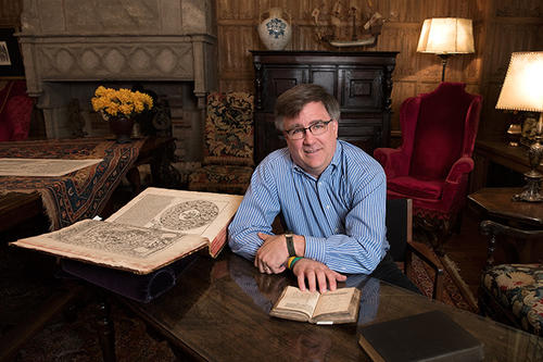 J.B. Shank, in glasses, at his desk with a large, open history book.