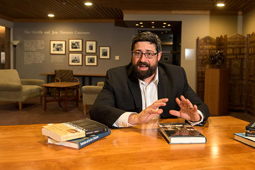 Joe Soss, with dark hair and beard and glasses, at his desk.