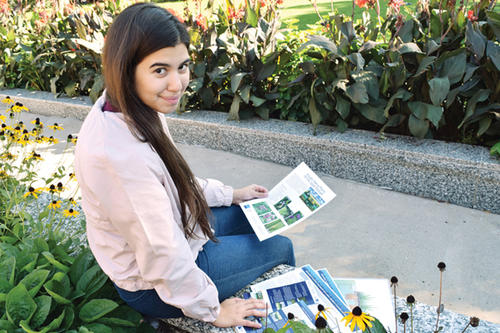 Maria Franco, with dark hair and eyes, sits holding plants.