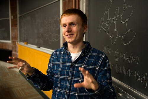 Max Shinn explains a concept in front of a blackboard.