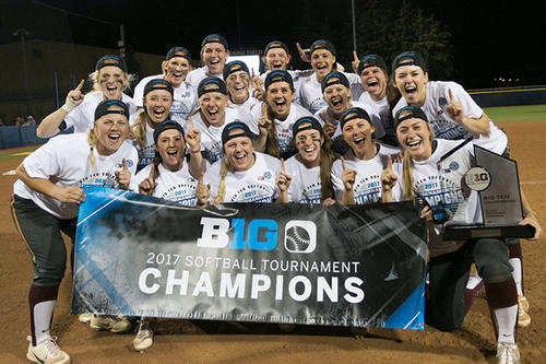 The Gopher softball team holds its banner for winning the Big Ten Tournament championship.
