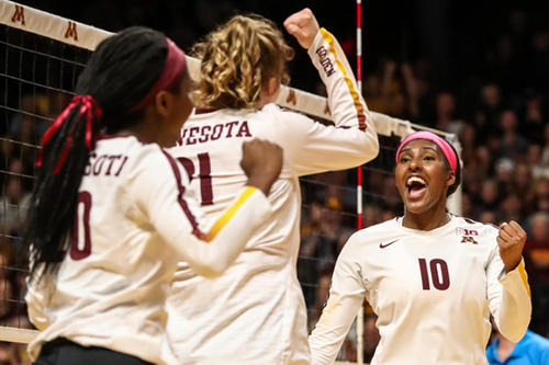 Three Gopher volleyball players celebrate a successful point.