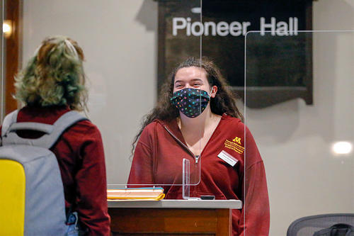 Woman wearing a mask talking to a student at Pioneer Hall