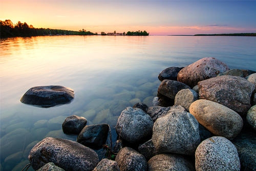 calm lake in autumn with round rocks on shore.