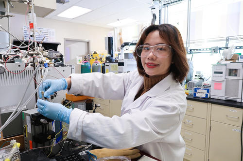 Yutong Pang wearing lab coat and glasses works in laboratory